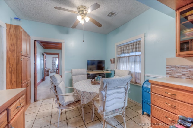 dining space with ceiling fan, light tile patterned flooring, and a textured ceiling