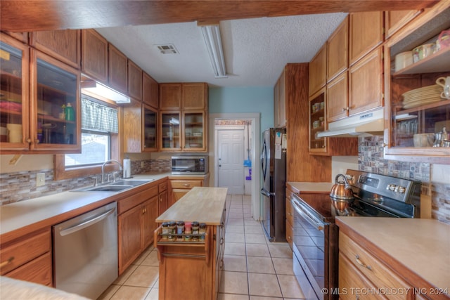 kitchen featuring light tile patterned flooring, stainless steel appliances, a kitchen island, and sink