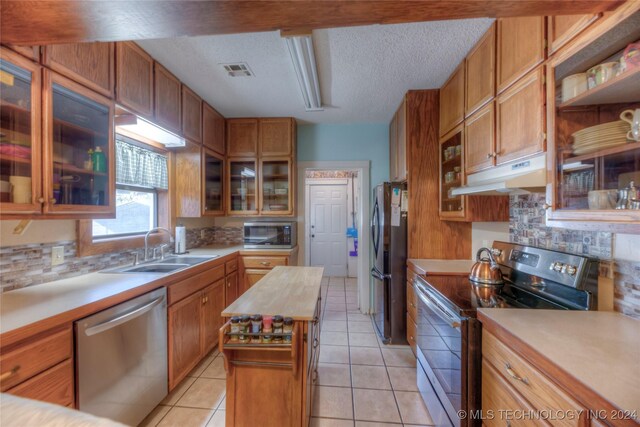 15705 Old Morris Hwy, Okmulgee, OK 74447 - kitchen featuring appliances with stainless steel finishes, under cabinet range hood, a sink, decorative backsplash, and a textured ceiling