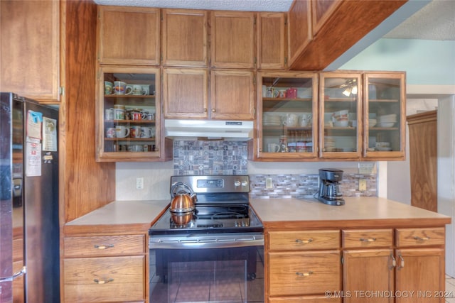 15705 Old Morris Hwy, Okmulgee, OK 74447 - kitchen featuring electric stove, under cabinet range hood, freestanding refrigerator, light countertops, and decorative backsplash