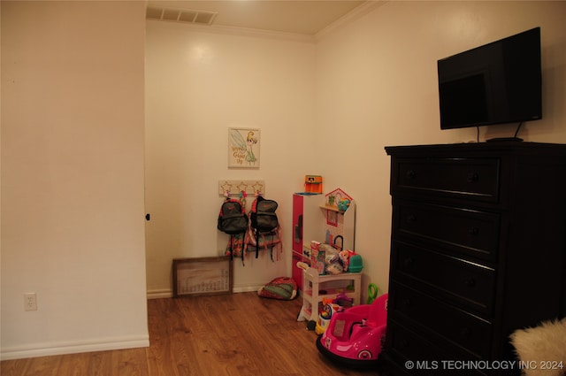 rec room with ornamental molding and light hardwood / wood-style floors