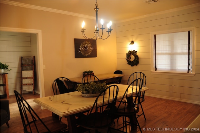 dining room featuring wood walls, dark wood-type flooring, crown molding, and an inviting chandelier