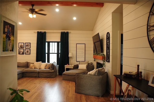 living room with wood walls, high vaulted ceiling, beamed ceiling, ceiling fan, and light wood-type flooring