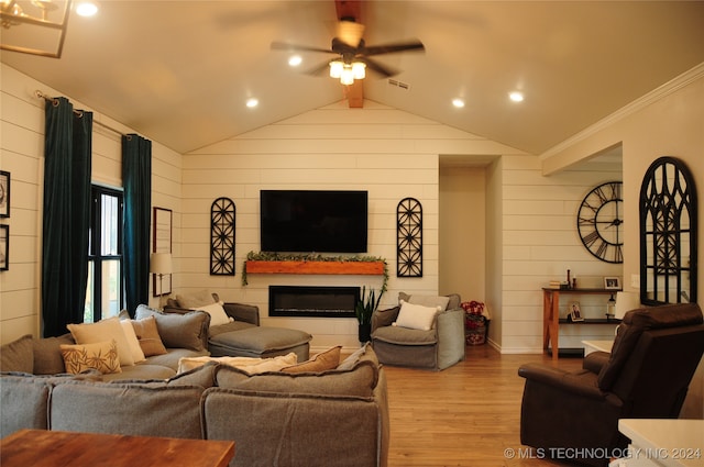 living room featuring lofted ceiling, wood walls, ceiling fan, crown molding, and light wood-type flooring