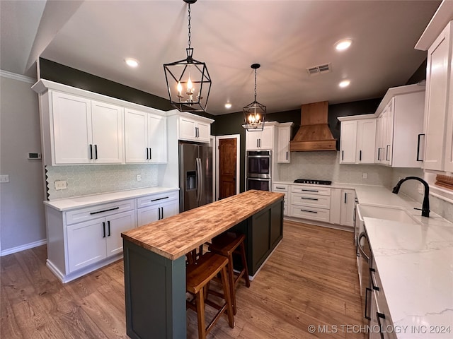 kitchen featuring white cabinets, stainless steel appliances, butcher block countertops, and a kitchen island