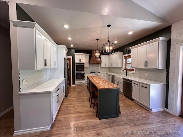 kitchen featuring premium range hood, wooden counters, appliances with stainless steel finishes, hanging light fixtures, and a center island