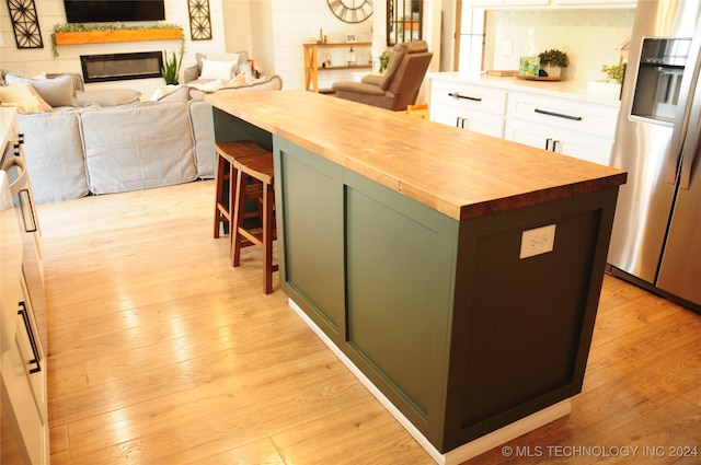 kitchen featuring white cabinetry, butcher block counters, a center island, and stainless steel fridge