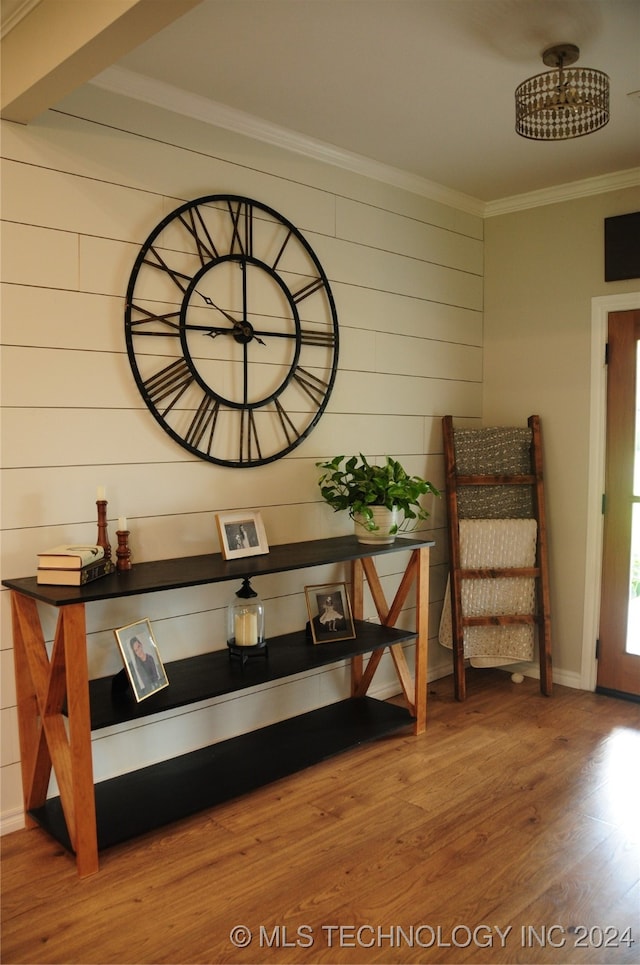 sitting room featuring hardwood / wood-style floors, wooden walls, and crown molding