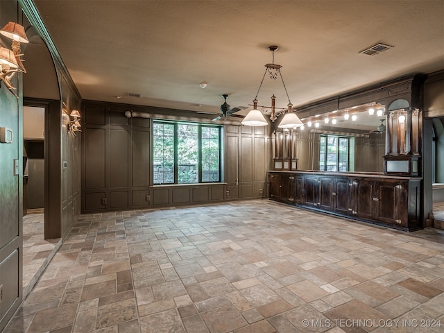 interior space featuring a textured ceiling, ceiling fan, dark brown cabinetry, and hanging light fixtures