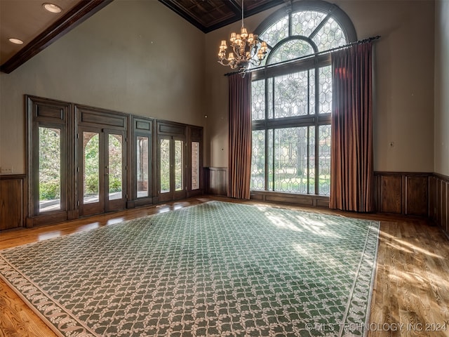 spare room featuring beam ceiling, high vaulted ceiling, a chandelier, and hardwood / wood-style flooring