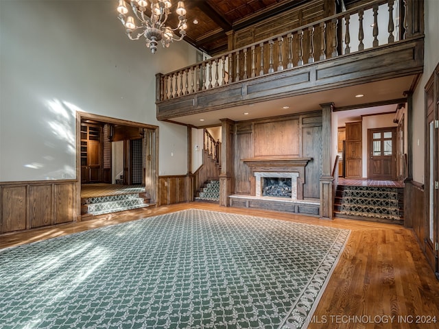 unfurnished living room with beam ceiling, a high ceiling, a chandelier, wood ceiling, and hardwood / wood-style flooring