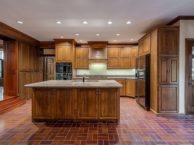 kitchen featuring refrigerator with ice dispenser, sink, an island with sink, and double oven