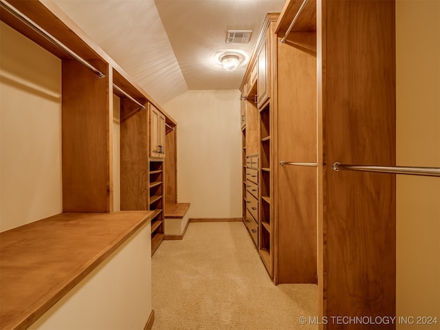 walk in closet with light carpet and vaulted ceiling