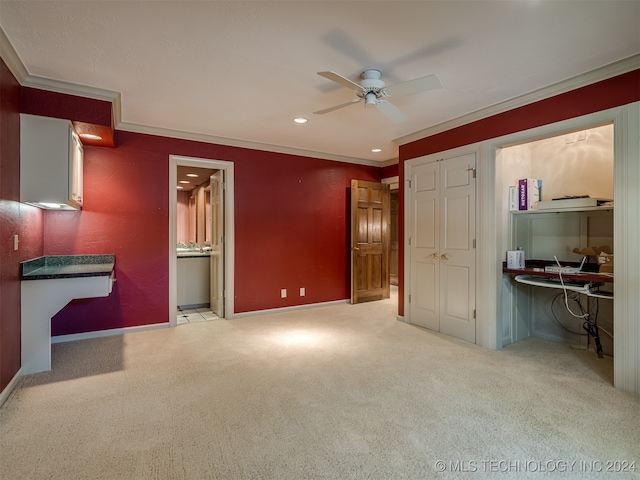 unfurnished bedroom featuring ceiling fan, crown molding, ensuite bathroom, and light carpet