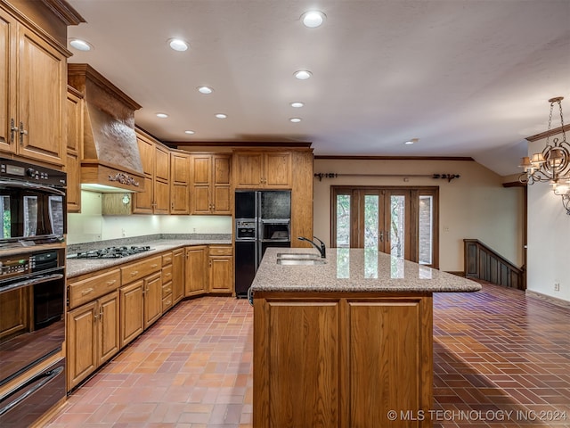 kitchen featuring a kitchen island with sink, black appliances, sink, hanging light fixtures, and custom range hood