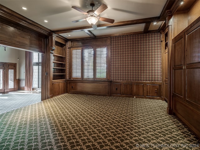 interior space featuring carpet flooring, wood walls, ceiling fan, and beam ceiling