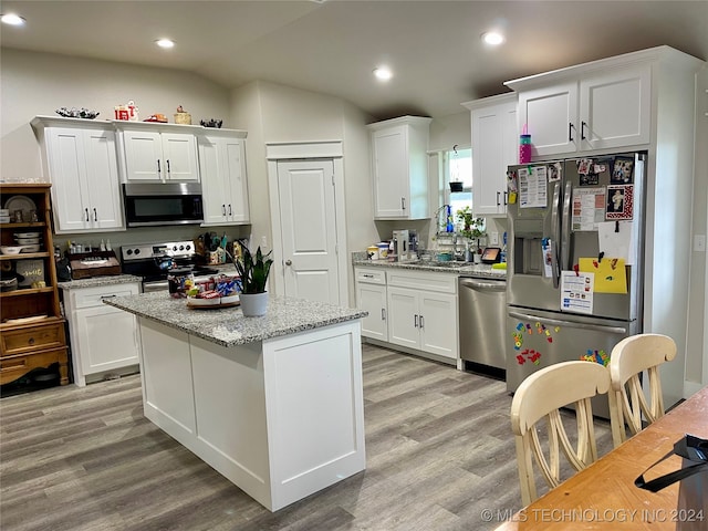 kitchen with light wood-type flooring, stainless steel appliances, white cabinetry, and light stone counters