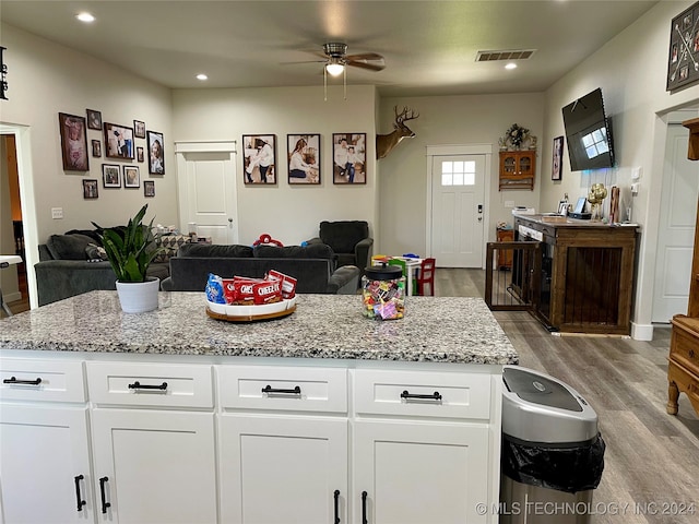 kitchen with white cabinets, light stone countertops, light hardwood / wood-style flooring, and ceiling fan