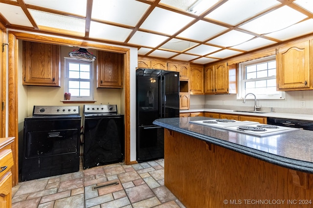 815 S Oak Grove Rd, Cushing, OK 74023 - kitchen featuring black appliances, washer and dryer, healthy amount of natural light, and brown cabinetry