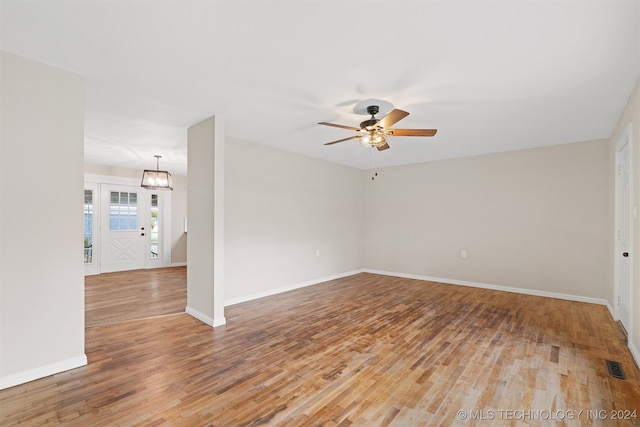 empty room with hardwood / wood-style flooring and ceiling fan with notable chandelier