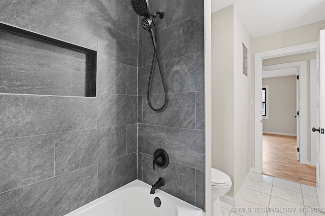 bathroom featuring tile patterned floors, toilet, and tiled shower / bath