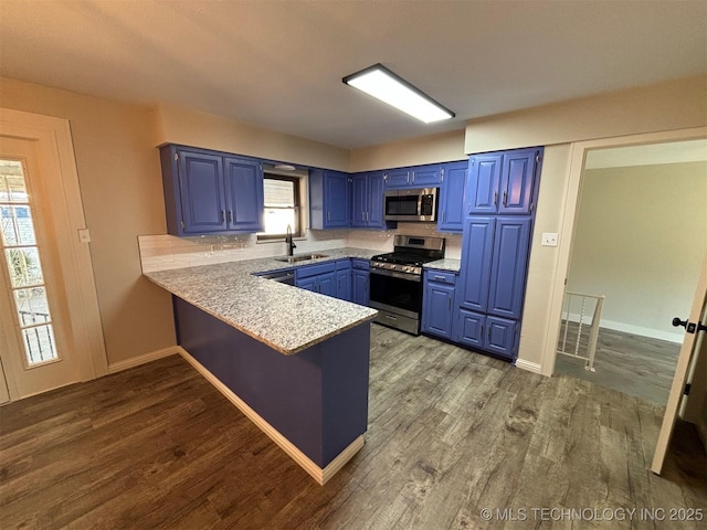 kitchen with sink, hardwood / wood-style flooring, blue cabinetry, appliances with stainless steel finishes, and kitchen peninsula