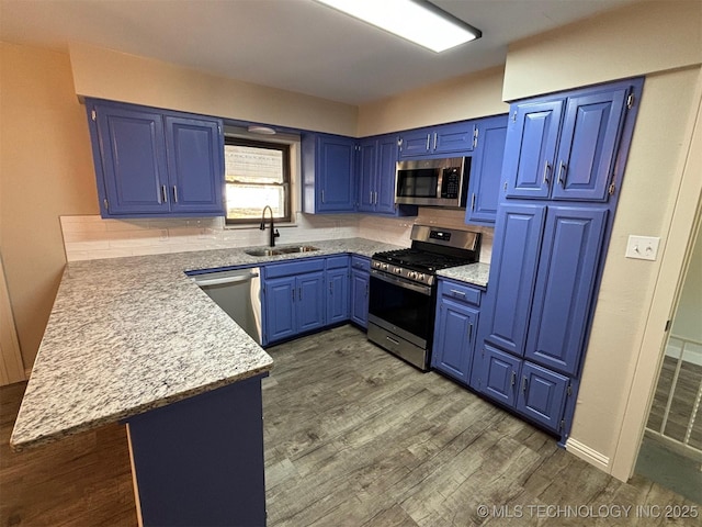 kitchen with kitchen peninsula, appliances with stainless steel finishes, blue cabinets, and sink