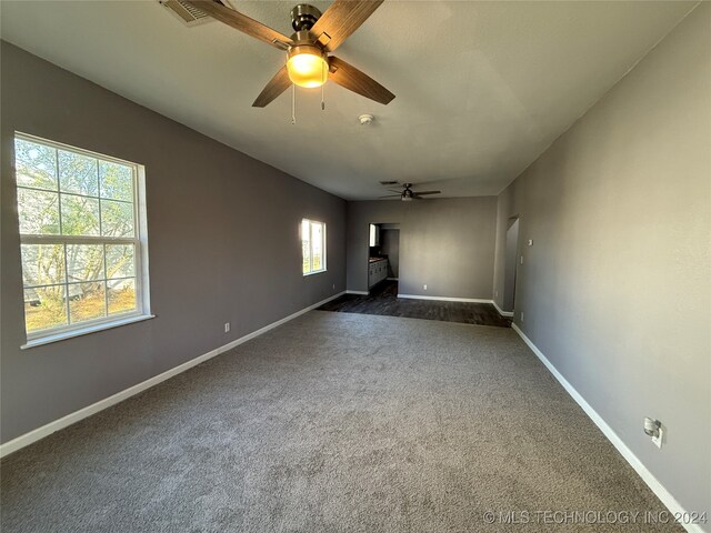 empty room featuring ceiling fan and dark carpet
