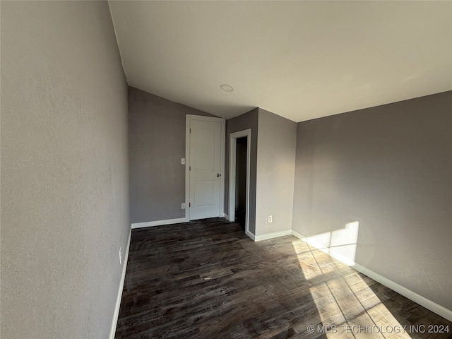 unfurnished room with dark hardwood / wood-style floors and vaulted ceiling