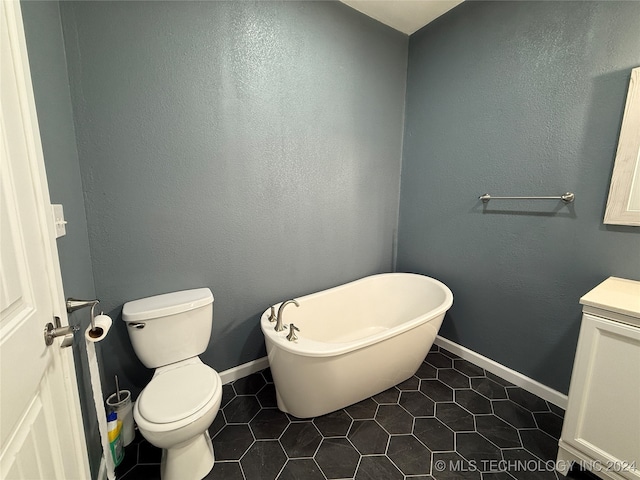 bathroom featuring toilet, a washtub, vanity, and tile patterned flooring