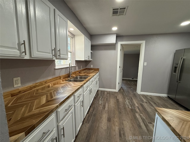 kitchen featuring wooden counters, white cabinetry, sink, and stainless steel fridge