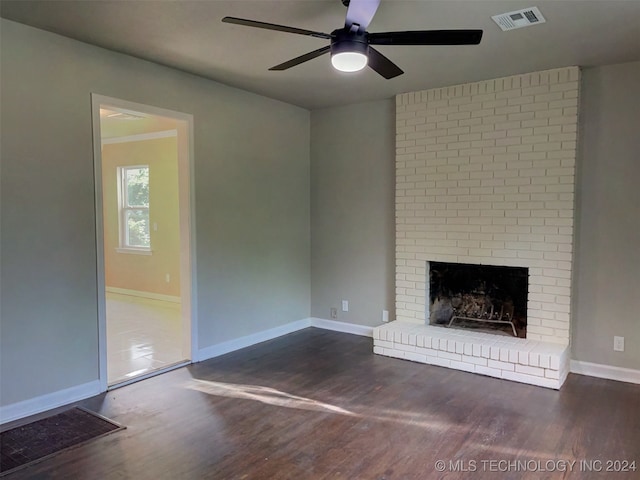 unfurnished living room with dark hardwood / wood-style flooring, ceiling fan, and a brick fireplace