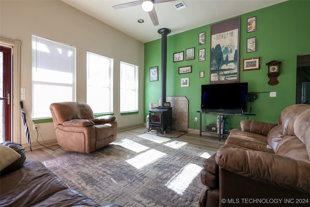 living room with light hardwood / wood-style floors, ceiling fan, and a wood stove