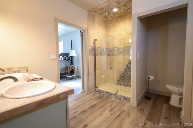 bathroom featuring hardwood / wood-style floors, a shower with shower door, vanity, and toilet