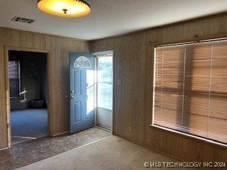 entryway with light colored carpet and wood walls