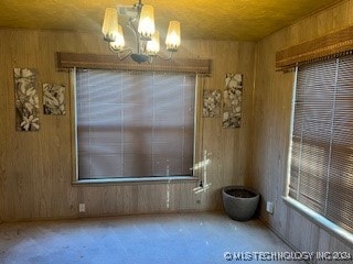 empty room featuring wood walls and a notable chandelier