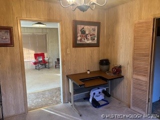 interior space with wood walls, carpet floors, and a notable chandelier