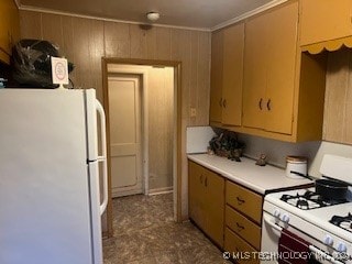 kitchen with white appliances, wooden walls, and ornamental molding