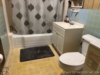 full bathroom featuring shower / tub combo with curtain, vanity, tile walls, and toilet