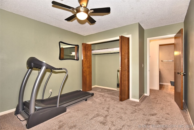 workout room featuring ceiling fan, light colored carpet, and a textured ceiling