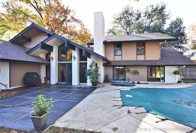 rear view of house featuring a patio and a covered pool