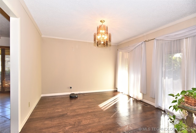 spare room featuring a textured ceiling, dark wood-type flooring, a healthy amount of sunlight, and a notable chandelier