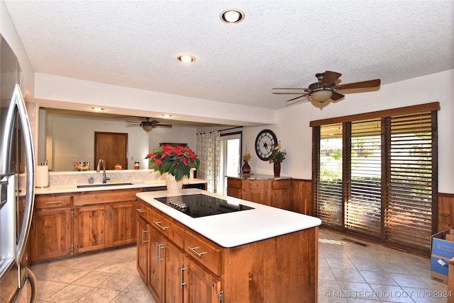 kitchen featuring a center island, sink, stainless steel fridge with ice dispenser, a textured ceiling, and black electric stovetop