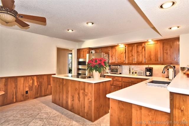 kitchen with sink, a center island, tasteful backsplash, a textured ceiling, and appliances with stainless steel finishes