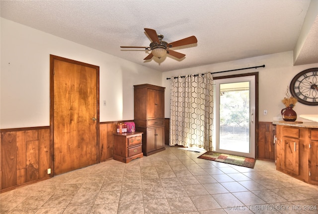 interior space with ceiling fan, wood walls, and a textured ceiling