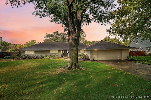 ranch-style house featuring a front lawn, an attached garage, fence, and driveway