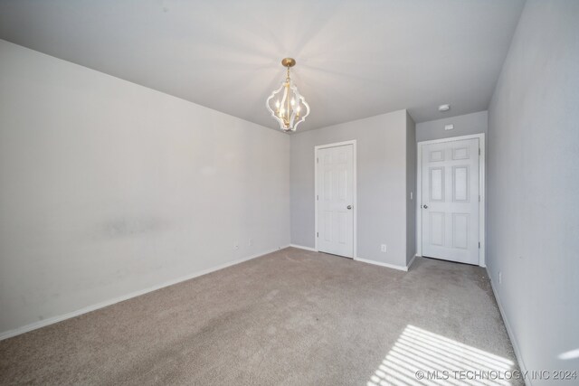 unfurnished bedroom featuring light carpet and an inviting chandelier