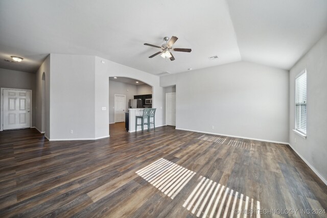 unfurnished living room with dark wood-type flooring, vaulted ceiling, and ceiling fan