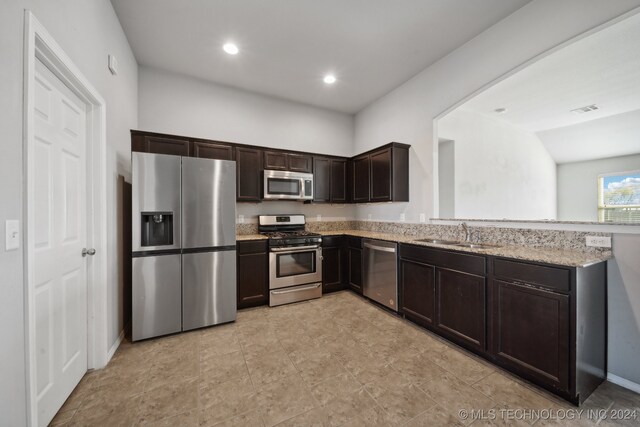 kitchen with dark brown cabinetry, light stone countertops, sink, and appliances with stainless steel finishes