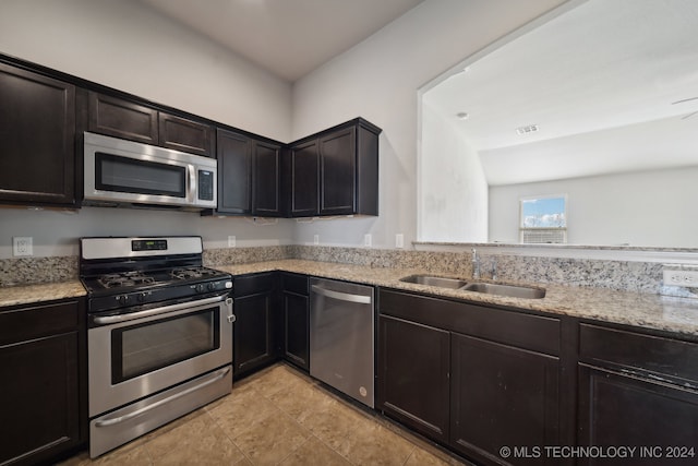 kitchen featuring stainless steel appliances, sink, and light stone counters